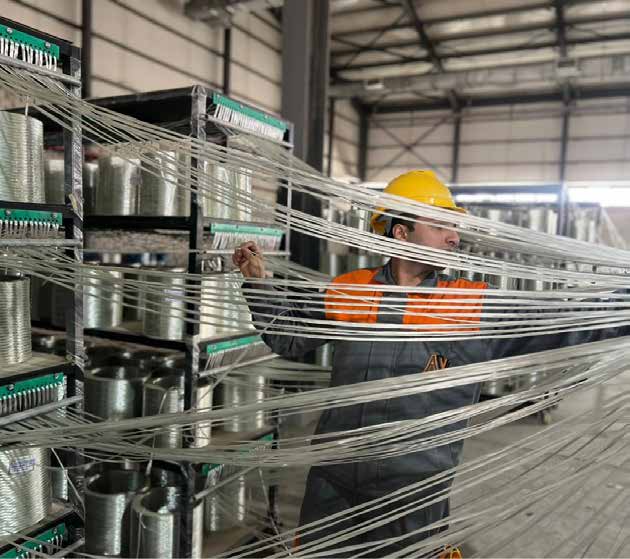 Worker handling glass fiber strands from spools